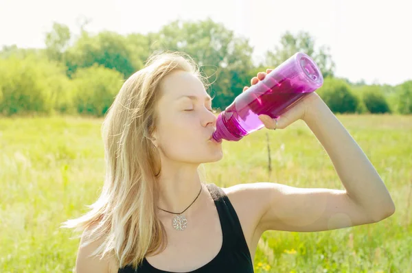 Mujer joven con una figura deportiva, cuerpo, delgado, después de un entrenamiento bebe agua de la botella —  Fotos de Stock