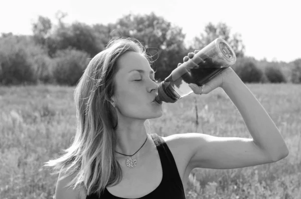 Muchacha muy hermosa bebiendo con impaciencia agua de una botella de calor, día de verano soleado, bw — Foto de Stock