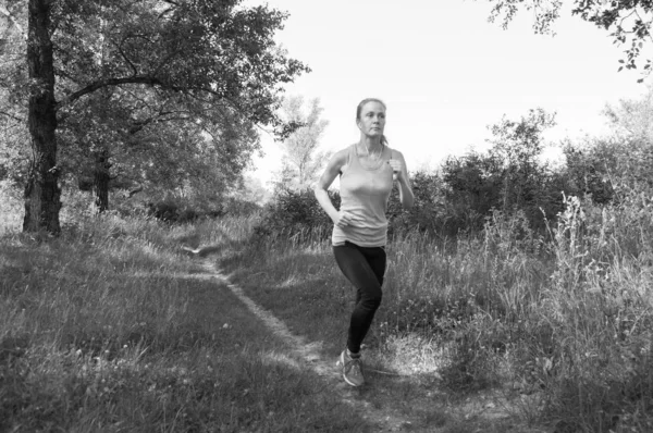 Atlética, hermosa chica corriendo en el parque o el bosque y escuchando música soleada mañana de verano, BW — Foto de Stock