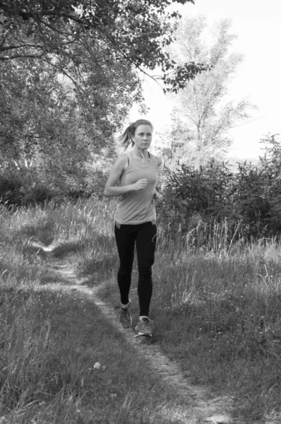 Atlética, hermosa chica corriendo en el parque o el bosque y escuchando música soleada mañana de verano, BW — Foto de Stock