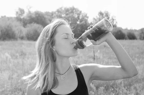 Deporte, chica bonita con ganas de beber agua de una botella en una tarde caliente en el parque, bw — Foto de Stock