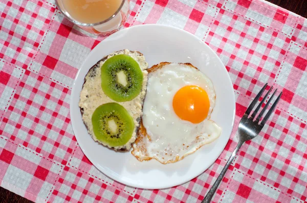 Zdravá a chutná snídaně, chinceová šťáva, celozrnný chlebový sendvič s kiwi a vajíčkem na bílé desce, růžový ubrousek — Stock fotografie