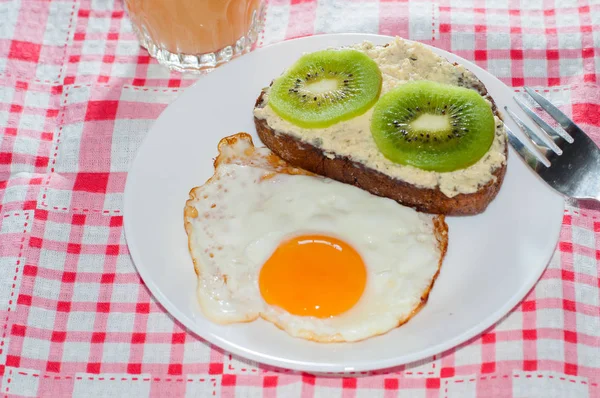 Café da manhã saudável, saboroso, suco de marmelo, sanduíche de kiwi de grãos integrais e ovo frito em um prato branco — Fotografia de Stock