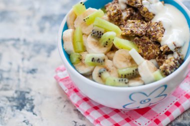 Granola, kivi, muz ve Yunan yoğurdu kırmızı bir peçete üzerinde, gri beton arka plan üzerinde kase içinde, üstten alan görünümü kopyalayın. Kilo kaybı, doğru beslenme ve sağlıklı bir yaşam tarzı için Fitness diyet