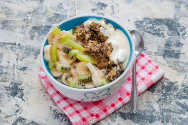 Granola, kivi, muz ve Yunan yoğurt gri beton arka plan üzerinde bir kase içinde, kırmızı bir peçete üzerinde, üstten alan görünümü kopyalayın. Kilo kaybı, doğru beslenme ve sağlıklı bir yaşam tarzı için Fitness diyet