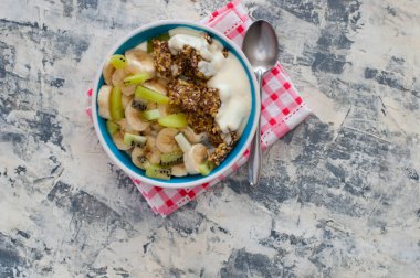 Granola, kivi, muz ve Yunan yoğurt gri beton arka plan üzerinde bir kase içinde, kırmızı bir peçete üzerinde, üstten alan görünümü kopyalayın. Kilo kaybı, doğru beslenme ve sağlıklı bir yaşam tarzı için Fitness diyet
