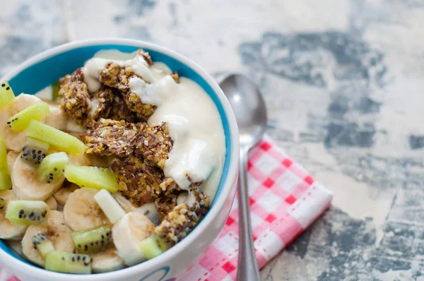 Granola, kiwi, banana and Greek yogurt in a bowl on a gray concrete background, on a red napkin, copy space view from the top. Fitness diet for weight loss, proper nutrition and a healthy lifestyle — Stock Photo, Image