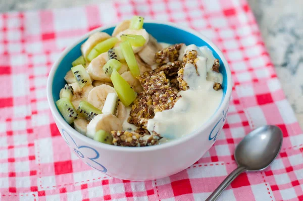 Granola Yunan yoğurt kivi ve muz ile kase de pembe bir peçete üzerinde bir kaşık, üstten görünümü. Kilo kaybı, uygun ve lezzetli gıda için Fitness diyet