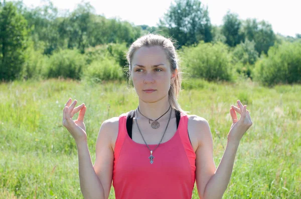 Joven hermosa mujer haciendo yoga sobre la naturaleza en verano. Chica delgada y muy agradable medita en la mañana soleada —  Fotos de Stock