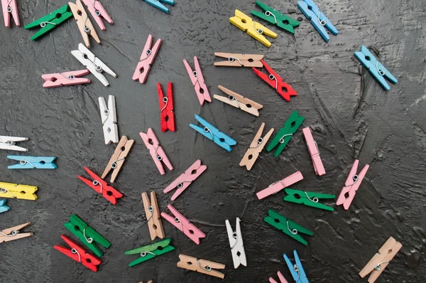 Handgefertigter Hintergrund, viele bunte Holzklammern auf dunkelgrauem Beton, Kopierraum — Stockfoto