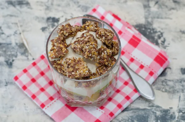 Granola, yaourt grec, kiwi et banane en bécher de verre sur une serviette rose à carreaux en béton gris, avec une cuillère pour copier l'espace, vue du haut. Fitness, silhouette, corps et alimentation saine — Photo