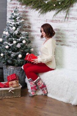 Noel ağacının yanında hediye olan çok güzel bir kız. Hediyeye bakar.