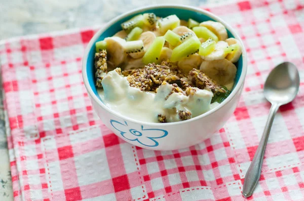 Granola with Greek yogurt kiwi and banana in bowl on a pink napkin, close-up view from the top. Fitness diet for weight loss, proper and tasty food — Stock Photo, Image