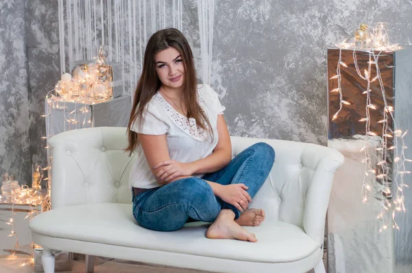 Hermosa chica alegre en un sofá blanco en el interior de Año Nuevo del apartamento — Foto de Stock