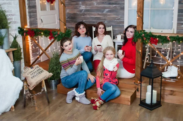 Varias mujeres muy bonitas y una adolescente celebran la Navidad, el año nuevo. Las niñas en el interior de Año Nuevo con copas en sus manos — Foto de Stock