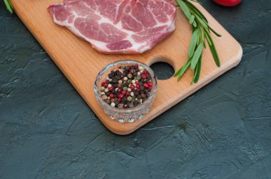 Çiğ et biftekleri, kırmızı domatesler, biberiye ve biber koyu arka planda, metin için alt yer