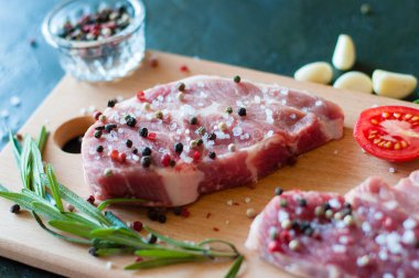 Biber ve tuz serpilmiş çiğ domuz eti doğranmış domates, sarımsak ve biberiye, biftek pişirme süreci.