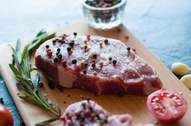 Biber ve tuz serpilmiş çiğ domuz eti doğranmış domates, sarımsak ve biberiye, biftek pişirme süreci.