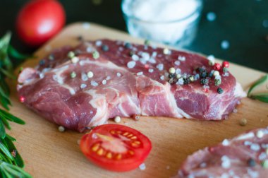 Biber ve tuz serpilmiş çiğ domuz eti, doğranmış domates ve biberiye pişirme süreci.