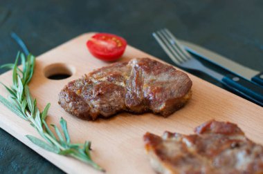 Et, bıçak ve çatal için ızgara dana eti veya domuz bifteği, domates, biberiye ve soya sosu