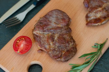 Izgara dana eti, biftek ya da domuz eti, domates, biberiye ve soya sosu et, bıçak ve çatal, ahşap bir tahtanın üzerinde, yakın plan, düz yatak