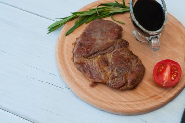 Düz uzanış, ahşap tahta üzerinde kızarmış domuz bifteği, soya sosu, biberiye ve domatesli, soldan kopyalanmış boşluk.