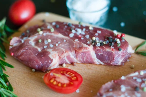 Biber ve tuz serpilmiş çiğ domuz eti, doğranmış domates ve biberiye pişirme süreci.