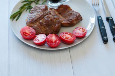 Kızarmış, çok lezzetli ve sulu domuz eti ya da soslu, baharatlı ve domatesli biftek, gri tabakta, fotokopi alanı için açık ahşap arka planda