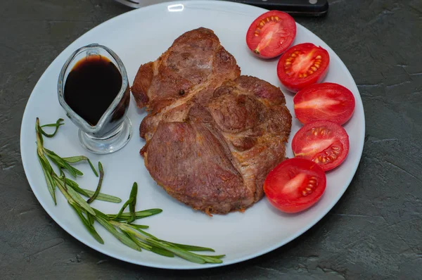 Szaftos hús steak rozmaringgal, szósszal, paradicsom egy tányéron, sötét szürke beton alapon — Stock Fotó