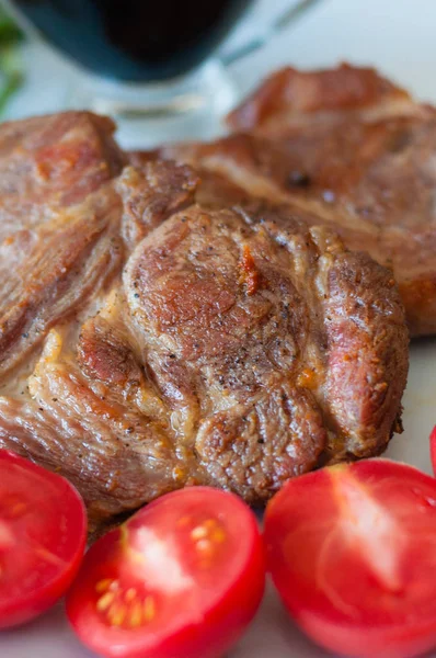 Duftende Schweinefleischsteaks mit Gewürzen, Tomaten und Soße auf einem grauen Teller, Nahaufnahme — Stockfoto