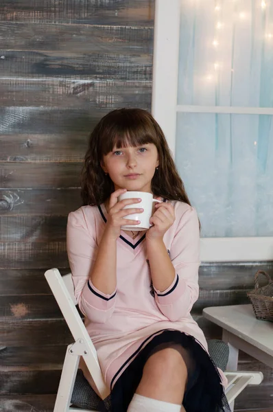 Menina adolescente bonita em vestido com xícara branca de chá na mesa, na varanda da casa — Fotografia de Stock