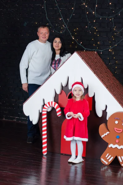 Piccola bella ragazza con i suoi genitori vicino casa di pan di zenzero di Natale — Foto Stock