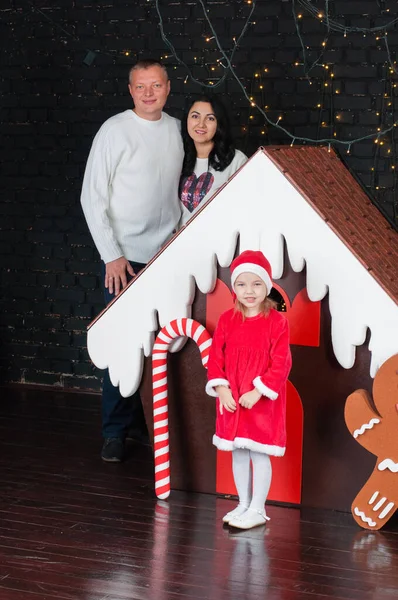 Piccola bella ragazza con i suoi genitori vicino casa di pan di zenzero di Natale — Foto Stock