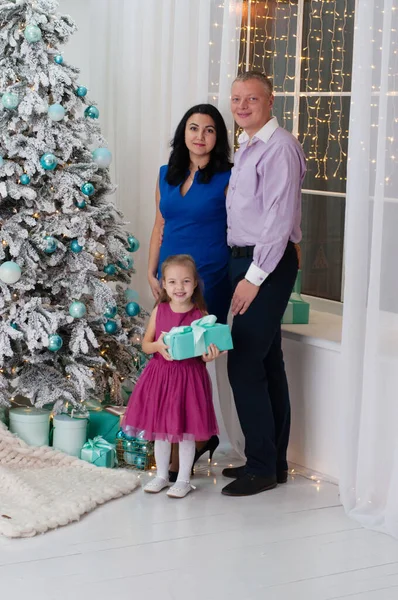 Famiglia vicino all'albero di Capodanno. Il bambino tiene in mano un dono — Foto Stock