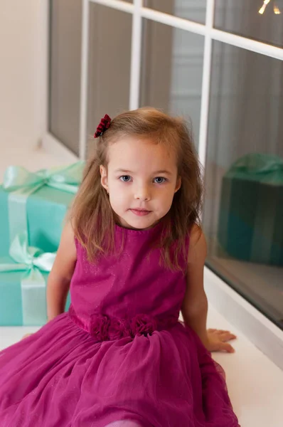 Menina sorridente bonito com presentes de Natal sentado no peitoril da janela — Fotografia de Stock