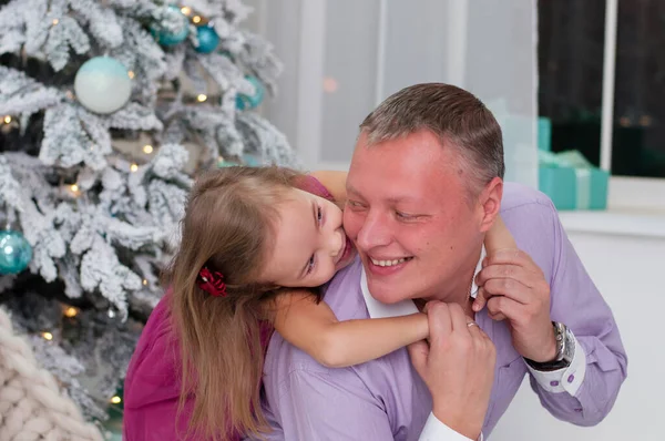 Baby girl laughing dabbles with dad near Christmas tree — ストック写真