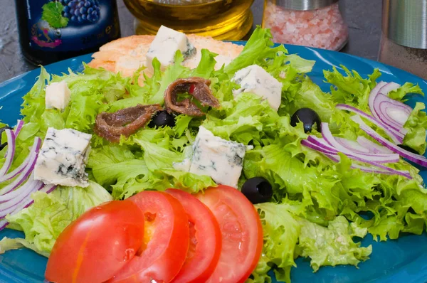 Σαλάτα με χταπόδι ή καλαμάρι, τυρί, ντομάτα, ελιές, κρεμμύδια, μπαχαρικά και κρουτόν, σάλτσα ή λάδι σε μπλε πιάτο — Φωτογραφία Αρχείου