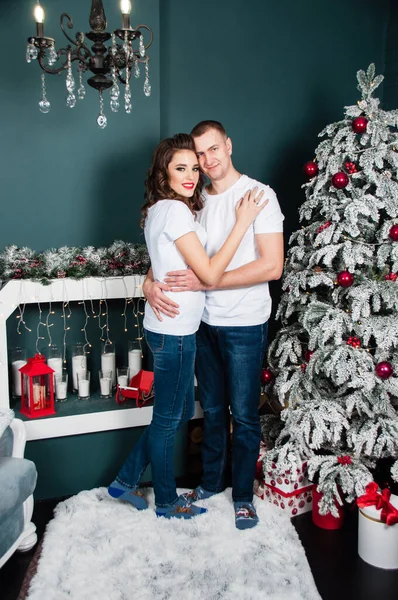 愛するカップル 夫と妻 男と女 抱擁し クリスマスツリーと暖炉の近くの新年のインテリアでお互いを見て — ストック写真