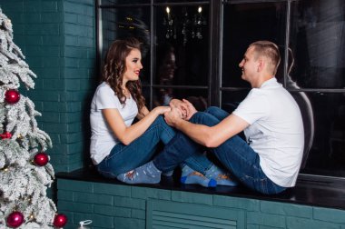 Aşıklar Noel ağacının yanındaki pencereye oturur ve nazikçe el ele tutuşurlar..