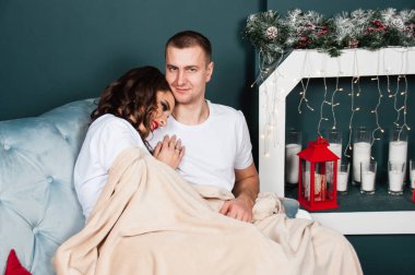 Sevgi dolu evli bir çift, zayıf, atletik bir erkek ve şöminenin yanındaki kanepede güzel bir kadın. Ekoseye sarılı oturan çift.