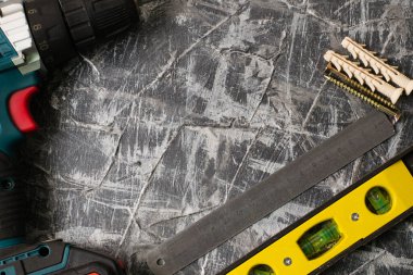 İnşaat seviyesi, tornavida, gri macunun arka planında metal cetvel kapakları. İnşaat, onarım, konut koşullarının iyileştirilmesi