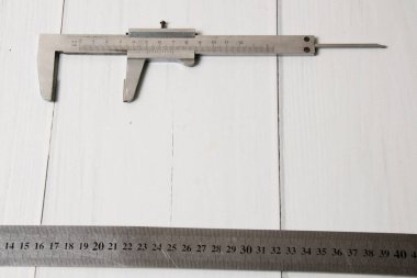 Açık ahşap arka planda, fotokopi alanı olan iki metal inşaat cetveli. İnşaat, onarım, konut koşullarının iyileştirilmesi