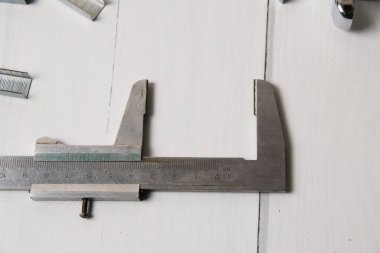 İnşa cetveli ve metal zımba zımbaları. Hafif ahşap arka planda fotokopi alanı var. İnşaat, onarım, konut koşullarının iyileştirilmesi