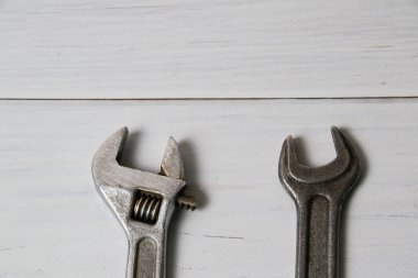 İki eski anahtar, ayarlanabilir anahtarlar ve yayıcılar, fotokopi alanı olan açık tahta bir arka planda.