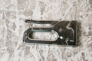 Tamir ve inşaat kavramı. Gri dekoratif macunun arka planında zımba bulunan zımba zımbası..