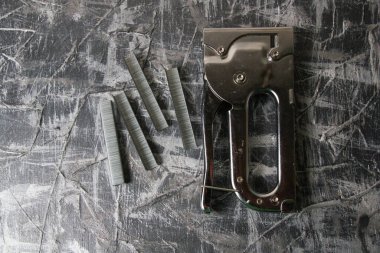 Tamir ve inşaat kavramı. Koyu gri dekoratif macunun arka planında yapı destekleri ve zımba zımbası, boşluğu kopyala.