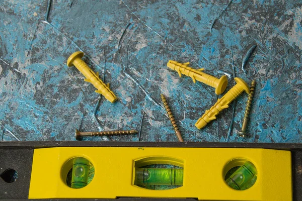 Construction level and dowels on blue putty wall. Concept repair of houses and apartments. — Stock Image Construction Level Dowels Blue Putty Wall Concept Repair Houses Apartments Royalty Free Stock Photos