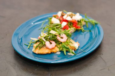 Karides, roka, domates, peynir ve sos, yakın plan, gri arka plan, yüksek İtalyan mutfağı.