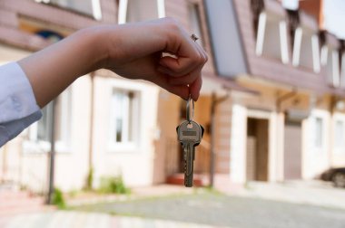 Şehrin iki katlı yeni ve güzel evlerinin arka planında bir kadının elinde dairenin anahtarları var.