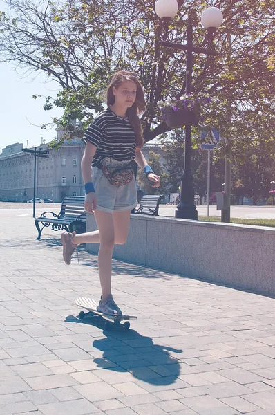 スレンダーティーンの女の子は 晴れた夏の日のヨーロッパの都市の中心部にある公園の路地をスケートボードに乗っています Instagramまたはヴィンテージ写真 — ストック写真